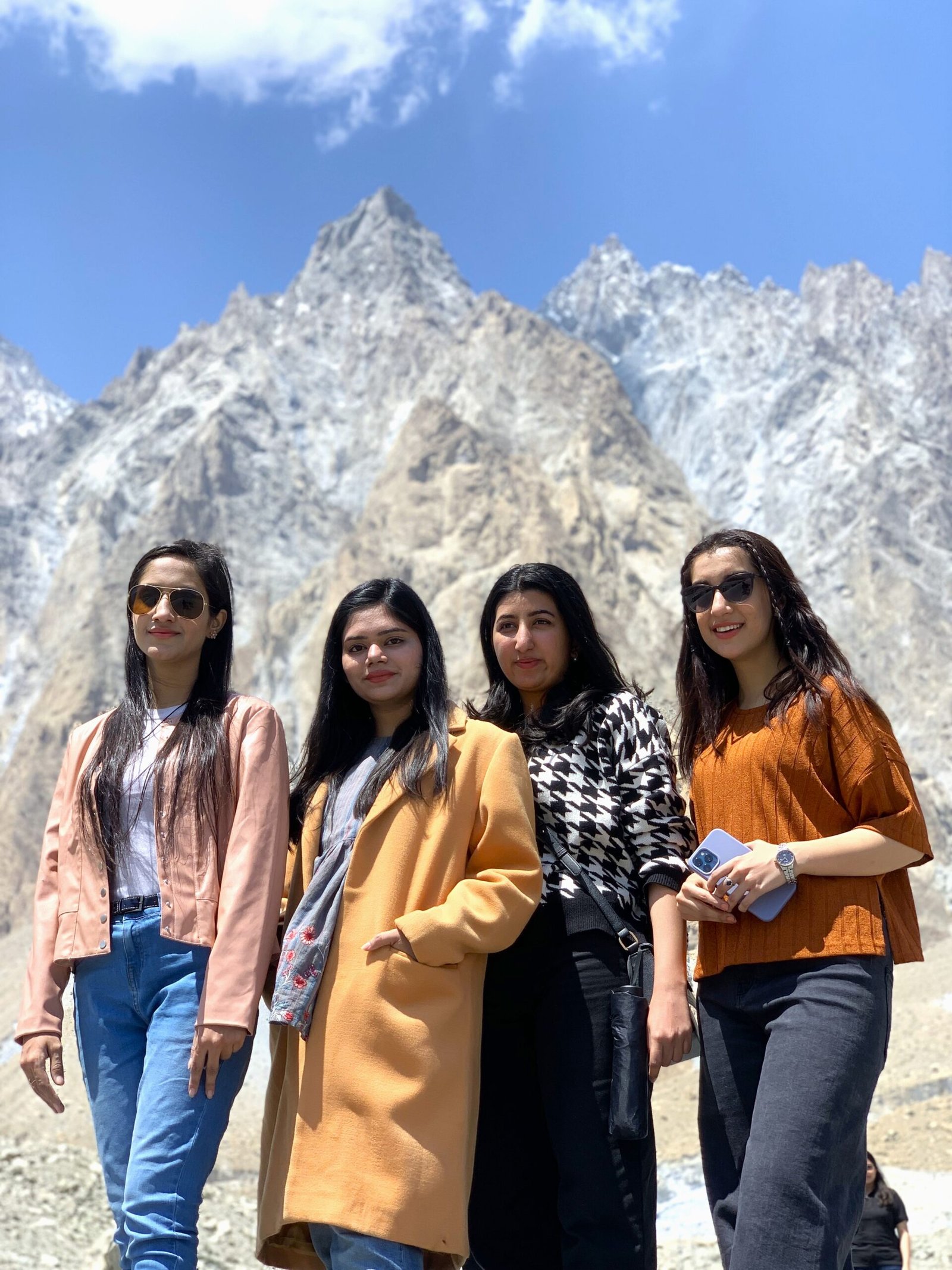 four girls standing in front of passu cones, Hunza, Pakistan